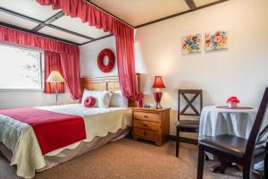 镭温泉Gables Motel的一间卧室配有一张带红色窗帘的床和一把椅子