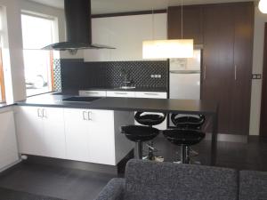 霍芬阿图恩公寓的厨房配有白色橱柜和带凳子的台面