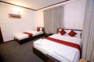 博卡拉Pokhara Backpackers Hostel的酒店客房 - 带两张带红色枕头的床
