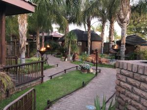 乌平通Country Lodge的棕榈树花园,砖砌走道