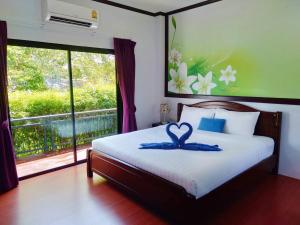 Ban Phlu Phliบลูออคิดรีสอร์ท ตรัง的一间卧室配有一张带蓝色丝带的床