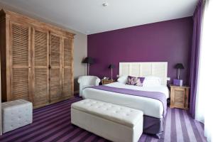 贝诺代Hotel Kastel & Spa avec piscine d'eau de mer chauffée的一间卧室设有一张大床和紫色的墙壁