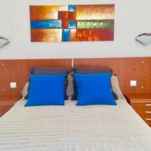 科斯塔德安提瓜Appartement vue mer et soleil toute l année的一张带蓝色枕头的床和墙上的绘画