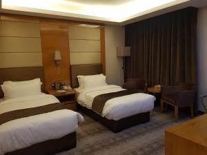 安曼Gloria Hotel的酒店客房带两张床和一张桌子以及椅子。