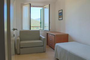 费拉约港阿雷葛罗塔利亚厄尔巴高尔夫酒店的卧室配有床、椅子和窗户。