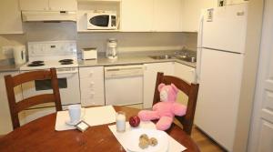 温哥华Times Square Suites Hotel的坐在厨房桌子上的粉红色泰迪熊