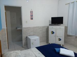 乌巴图巴Suítes Veleiro的一间卧室配有一张床,并在橱柜上配有电视