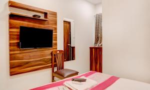 孟买Hotel Plaza Executive - near BKC的一间卧室配有一张床、一台电视和一把椅子