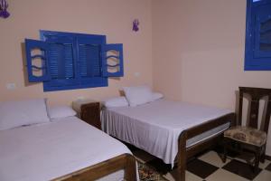 法尤姆Tunis Village Chalet的带蓝色百叶窗的客房内的两张床