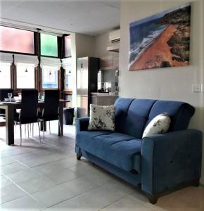 维多利亚85 Palma Living的客厅设有蓝色沙发,配有厨房