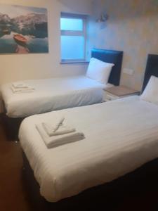 伯明翰The Saltley Inn的配有白色床单的酒店客房内的两张床