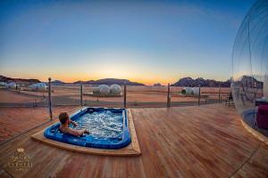 瓦迪拉姆Wadi Rum Bubble Luxotel的坐在甲板上热水浴池里的男孩