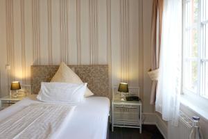 威斯巴登阿姆舒洛斯布里希酒店的一间卧室配有一张床和两张带台灯的桌子。
