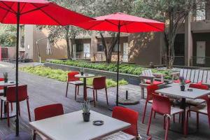 约翰内斯堡The Nicol Hotel Bedfordview的一个带桌椅和红色遮阳伞的庭院