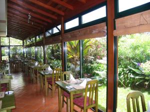 卡列塔大西洋花园酒店的用餐室设有桌椅和窗户。