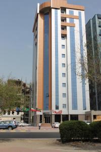 科威特拉古娜套房公寓的一座高大的建筑,前面有一辆汽车