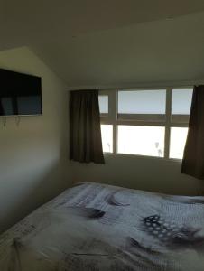 米德尔克尔克Huisje aan zee的一间卧室设有一张大床和一个窗户。