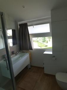 米德尔克尔克Huisje aan zee的带浴缸、水槽和窗户的浴室