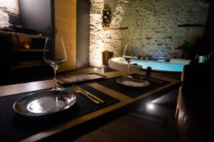 MédisLOVE Suites & SPA "Le Chai" avec lit rond的一张桌子、两杯酒和浴缸