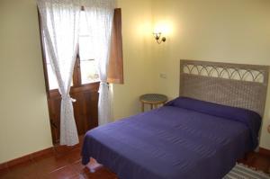 LamuñoApartamentos Rurales La Regatina的一间卧室设有紫色的床和窗户