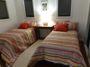 皮克顿Charolais Cottage的客房配有两张带红色枕头和桌子的床。