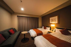松山多格酒店的酒店客房,设有两张床和一张沙发