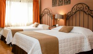 圣萨尔瓦多Las Magnolias Hotel Boutique的配有橙色窗帘的酒店客房的两张床