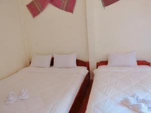 NongkhiawSythane Guesthouse的小客房内的两张床,配有白色床单