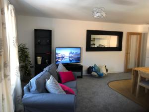 里彭Luxury Two Bed Apartment in the City of Ripon, North Yorkshire的客厅配有蓝色的沙发和平面电视。