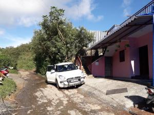 蒙纳Munnar Brindavan Cottage的停在房子旁边的土路上的一辆白色卡车