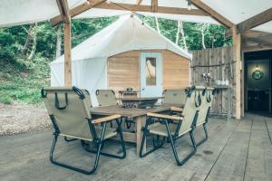 富士河口湖Retreat Camp Mahoroba的帐篷,甲板上配有木桌和椅子