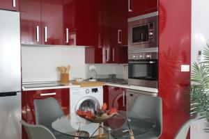 托莱多Apartamento Homelife Roca Tarpeya 4的厨房配有红色橱柜和玻璃桌椅