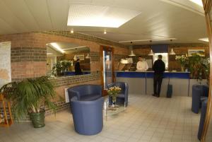 法什蒂梅斯尼勒阿杰那酒店的一间设有蓝色椅子的餐厅和一个柜台上的男人