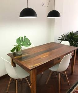 罗萨里奥Depto centrico, 90 m2, 2 habitaciones的一张带白色椅子的木桌和盆栽植物