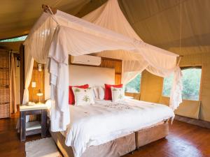 马迪克韦狩猎保护区aha Thakadu River Camp的一间帐篷内带天蓬床的卧室