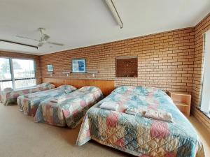 伊登湾景汽车旅馆的带三张床和砖墙的房间