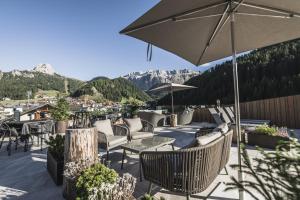 塞尔瓦迪加尔代纳山谷Hotel Chalet S - Dolomites Design - adults recommended的庭院配有桌椅和遮阳伞。