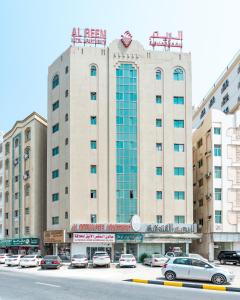 沙迦Al Reem Hotel Apartments的停车场内停放汽车的大型建筑