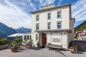 维森Boutique-Hotel Garni Bellevue Davos Wiesen的酒店大楼前面设有长凳