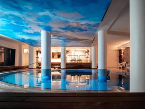 波尔托罗Boutique Hotel Portorose的一座房子,拥有一个游泳池,天花板上满是云