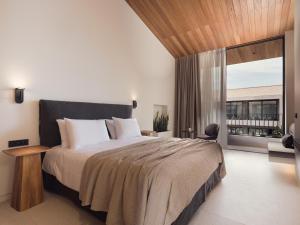 蒂锡利维Contessina Suites & Spa - Adults Only的一间卧室设有一张大床和一个大窗户