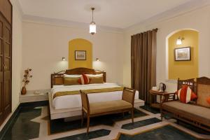 哈里瓦The Haveli Hari Ganga by Leisure Hotels的一间卧室配有一张床、一把椅子和一张沙发