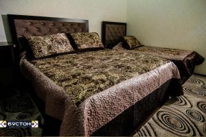 ChkalovskHotel Buston的一间卧室配有一张大床、床罩和枕头