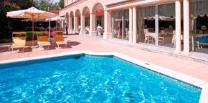 卢加诺德拉帕斯酒店的一座带椅子和遮阳伞的游泳池位于大楼旁