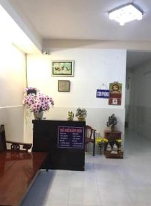 龙川市Nhà nghỉ Hoàng Huân的墙上挂着鲜花和标志的等候室