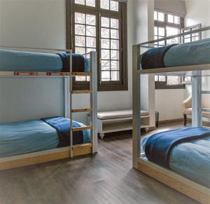 圣地亚哥Pariwana Hostel Santiago的客房设有三张双层床,配有蓝色床单