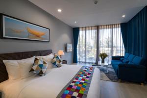 会安Beach Haven Suites Hội An Apartment的一间卧室配有一张大床和一张蓝色的沙发