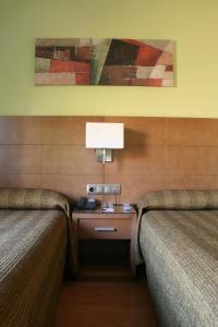 马德里欧罗巴皮尔塔4C酒店的酒店客房设有两张床和一张带台灯的桌子。