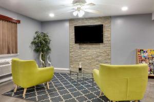 圣安东尼奥Super 8 by Wyndham San Antonio Pearl District Downtown的客厅配有2把黄色椅子和电视