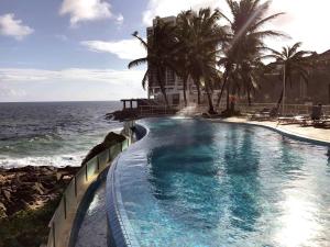 萨尔瓦多萨尔瓦多里奥福米罗美居酒店的毗邻大海的棕榈树游泳池